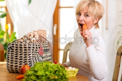 Woman with groceries eating carrot 