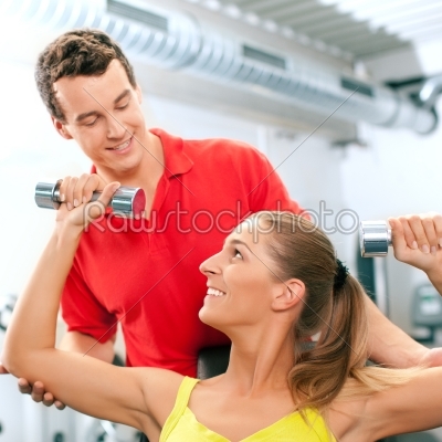 Woman with trainer and dumbbells in gym
