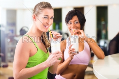 women in the gym drinking a isotonic drink or protein shake 