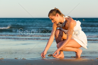 Women looking for sea shells in romantic sunset
