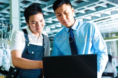 Worker and supervisor with laptop in a factory