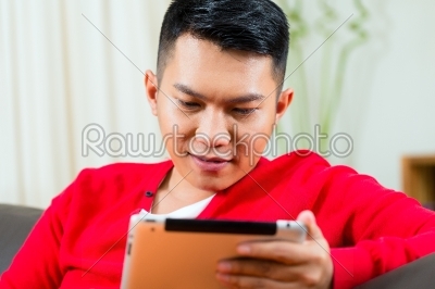 Young Asian man at home on the sofa