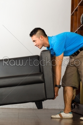 Young asian man lifting a couch