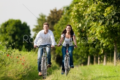 young couple cycling with bicycle in summer