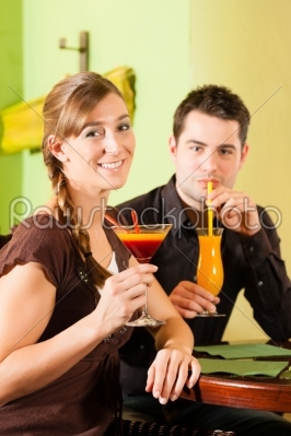 Young couple drinking cocktails in bar or restaurant