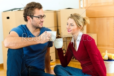 Young couple having break while moving in