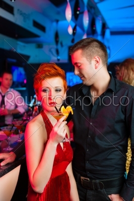 Young couple in bar or club drinking cocktails