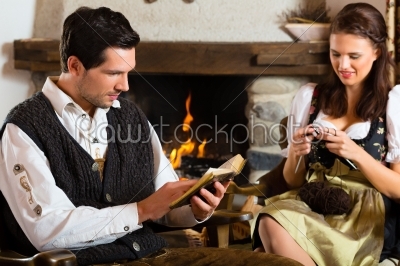Young couple in mountain hut at fire place