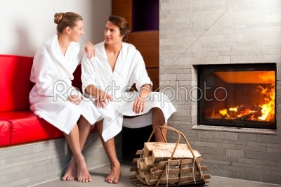 Young couple sitting in bathrobe for open fireplace