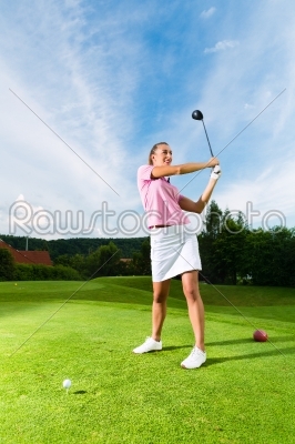 Young female golf player on course doing golf swing