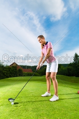 Young female golf player on course doing golf swing