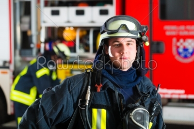 young fireman in uniform in front of firetruck