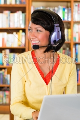 Young Girl in library with laptop and headphones