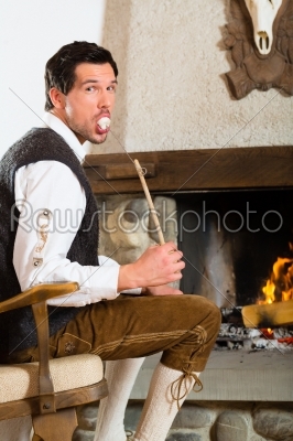 Young man in hunter_qt_s cabin eating marshmallow