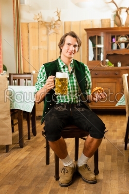 Young man in traditional Bavarian Tracht in restaurant or pub