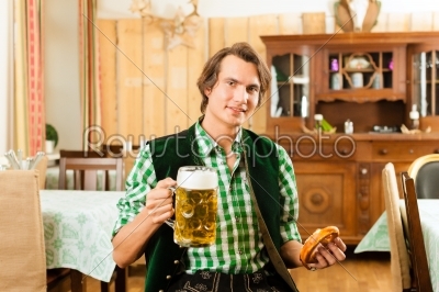Young man in traditional Bavarian Tracht in restaurant or pub
