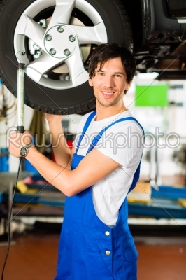 Young mechanic in blue overall working on car