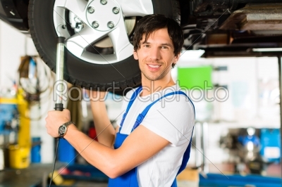 Young mechanic in blue overall working on car