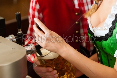 Young woman drawing beer in restaurant or pub