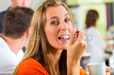 Young woman eating cream in cafe