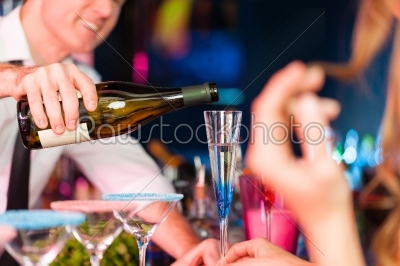 Young woman in club or bar drinking champagne