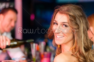 Young woman in club or bar drinking champagne