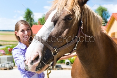 Young woman in the stable with horse and is happy