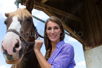Young woman in the stable with horse at sunshine
