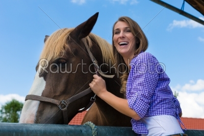 Young woman in the stable with horse at sunshine