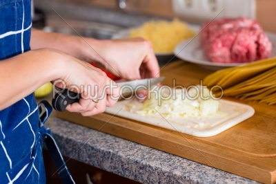 Young woman is cooking and chopping onions