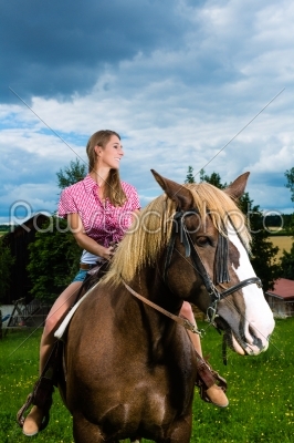Young woman riding the horses on the meadow