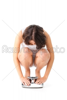 Young woman sitting on her haunches on a scale