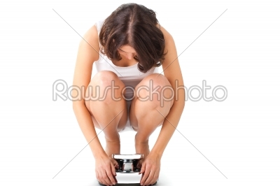 Young woman sitting on her haunches on a scale