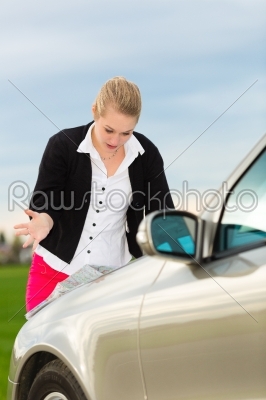 Young woman with map on car being lost 