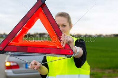 Young woman with warning triangle on street