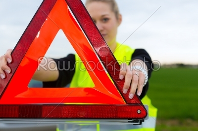Young woman with warning triangle on street