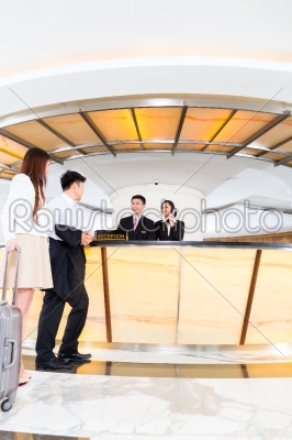 Asian Chinese couple arriving at hotel front desk