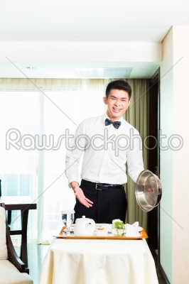 Asian Chinese room waiter serving guests food in hotel