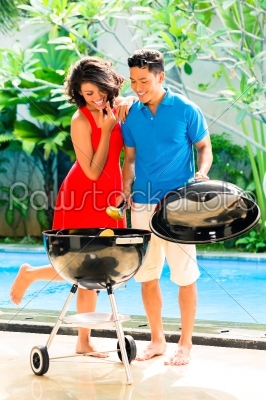 Asian couple having barbecue at the pool 