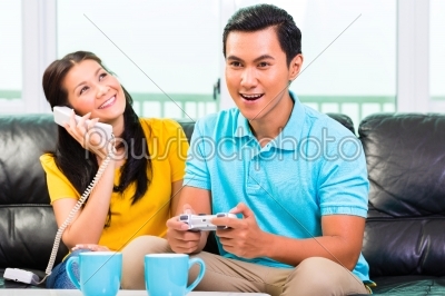 Asian couple playing video games and phone