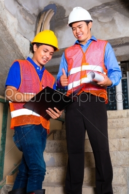 Asian supervisor and worker on building site 