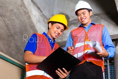 Asian supervisor and worker on building site 