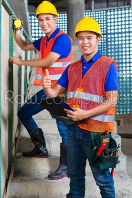 Asian worker controlling building on construction site