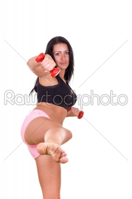 attractive woman giving a kick with leg lifting dumbbells