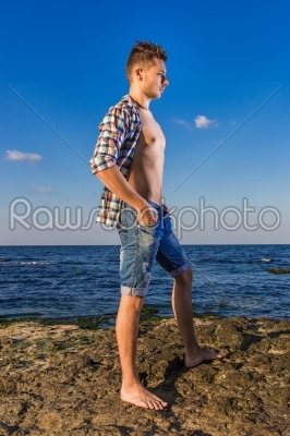Attractive young fashion sexy man on rock near the sea water