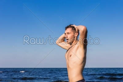 Attractive young man in the sea getting out of water
