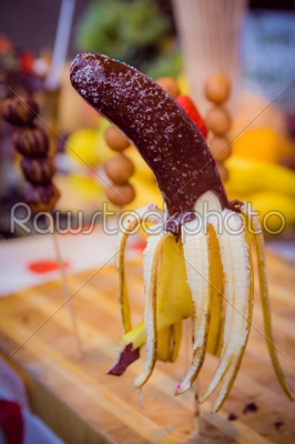 Banana on a stick coated chocolate with coconut chips and colore