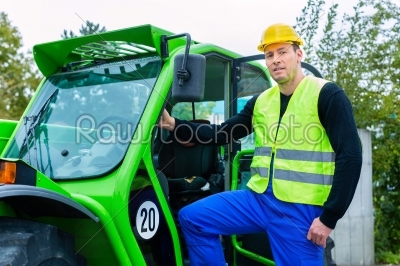 Builder on site in front of  construction machinery