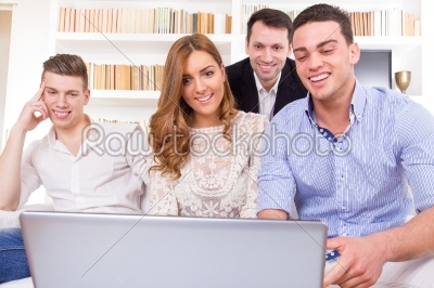 casual group of friends sitting on couch looking at laptop