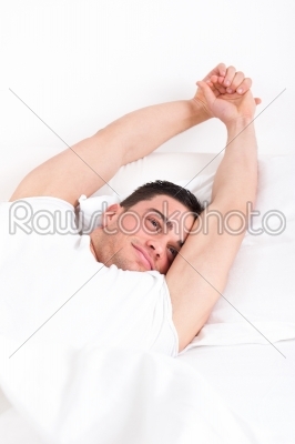 casual man waking up in the bedroom and stretches in be